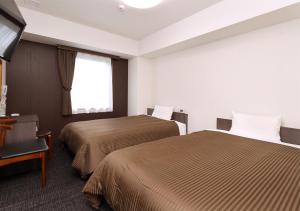 a hotel room with two beds and a window at Hotel Trend Okayama Ekimae in Okayama