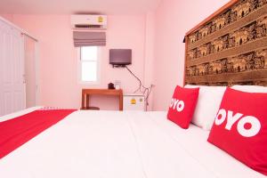 um quarto com uma grande cama branca com almofadas vermelhas em OYO 587 Baan Taklom Chomtalay em Cha Am