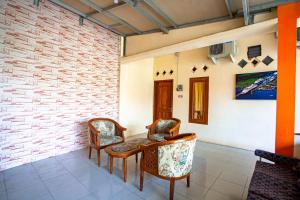 two chairs and a table in a room with a brick wall at SPOT ON 2875 Kost Pandawa Syariah in Cilacap