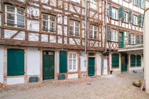 ein altes Gebäude mit grünen Türen und Fenstern in der Unterkunft Appartements Orfèvres Cathédrale in Straßburg