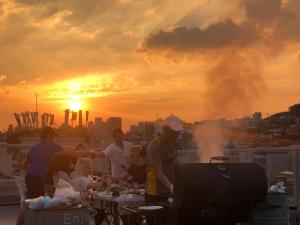 un grupo de personas sentadas en una azotea al atardecer en G Guesthouse Itaewon In Seoul en Seúl