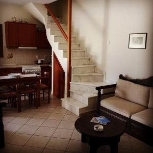a living room with a staircase and a couch and a table at To Pithari in Skiros