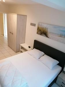 een slaapkamer met een wit bed en een foto van een strand bij Oostende Appartement in Oostende