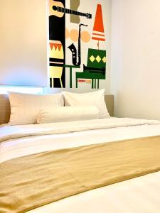 a bed with white sheets and a painting on the wall at Front One Cabin Sunter in Jakarta