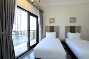 two beds in a room with a large window at Marbella Holiday Homes in Dubai