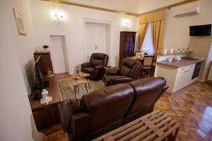 a living room with a brown leather couch and chairs at Little Vienna Gold Apartment in Varaždin