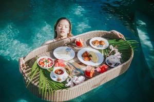 a woman in the water holding a tray of food in the water at Uma Mani Villa Bali in Jimbaran