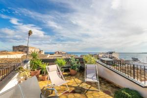 a balcony with chairs and a view of the ocean at Archimede apartments in Siracusa