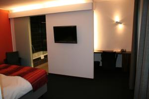 Habitación de hotel con cama y TV en la pared en Hotel Carpinus, en Lovaina