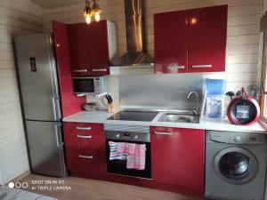 cocina con armarios rojos y nevera de acero inoxidable en Casa Ecoeficiente Eguzkilore, en Torrelles