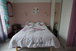 a bed with white sheets and pink flowers on it at O'jardin in Arthez-de-Béarn