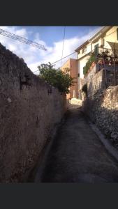 an alley with a stone wall and a building at B&B Piccolo Paradiso in Finale Ligure