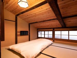a bedroom with a large bed in a room with wooden ceilings at Kanade Matsubaragokomachi-Momijittei in Kyoto