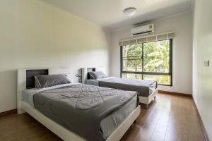 a bedroom with two beds and a window at Summer Resort in Nakhon Nayok in Nakhon Nayok