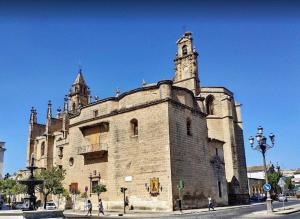 Un gran edificio de piedra con una torre en la parte superior. en APARTAMENTOs IGLESIA DE SANTIAGO, en Jerez de la Frontera