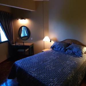 a bedroom with a bed with a blue comforter and a mirror at Seri Bulan Condo in Port Dickson