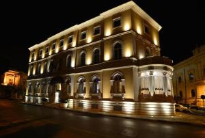 ein beleuchtetes Gebäude in der Nacht auf einer Straße in der Unterkunft Grand Hotel Ortigia in Syrakus