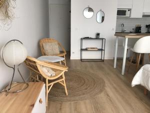 ein Wohnzimmer mit Stühlen und einem Tisch sowie eine Küche in der Unterkunft Studio neuf , à 2 pas de la plage et du port in Le Pouliguen