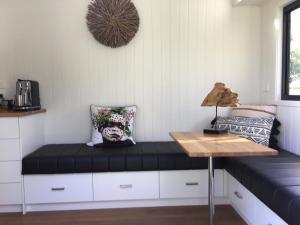 um quarto com um banco com almofadas e uma mesa em Tiny House em Woonona