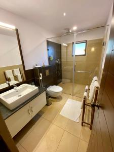 ein Bad mit einem Waschbecken, einem WC und einer Dusche in der Unterkunft Machaan Plantation Resort, Sakleshpur in Sakleshpur