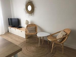 ein Wohnzimmer mit 2 Stühlen, einem Tisch und einem TV in der Unterkunft Studio neuf , à 2 pas de la plage et du port in Le Pouliguen