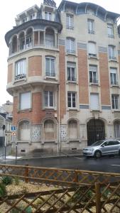 a building with a car parked in front of it at Studio Cosy 2 adultes in Reims