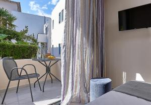 a bedroom with a balcony with a table and a television at Castello Village Resort in Sissi