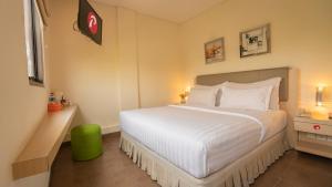 una camera da letto con un grande letto bianco e uno sgabello verde di d'primahotel Airport Jakarta 1 a Tangerang