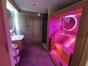 bagno con doccia rosa illuminata e lavandino di Gite Ni vu ni connu a Guînes