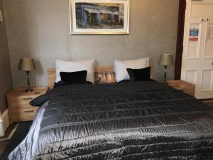 a bedroom with a large black bed with two lamps at Hannahs Guesthouse in Aberdeen