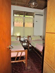 Habitación con 3 camas, mesa y ventana en Felipa Beach and Guesthouse - Lotus, en Dumaguete