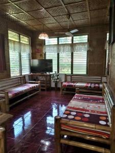 sala de estar con bancos y TV de pantalla plana en Felipa Beach and Guesthouse - Lotus, en Dumaguete