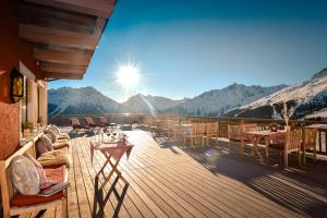 eine Terrasse mit Tischen und Stühlen und die Sonne scheint in der Unterkunft Hotel Alpenfriede in Sölden