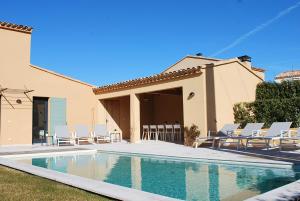 a swimming pool with chairs and a house at Villa Marièle in Malaucène