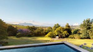a swimming pool with a view of a garden at Sugarbird Manor in Stellenbosch