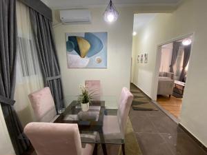 une salle à manger avec une table en verre et des chaises roses dans l'établissement Maspero Nile View Serviced Apartments by Brassbell, au Caire