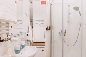 Un baño blanco con ducha y lavabo. en Sopot Host Molo, en Sopot