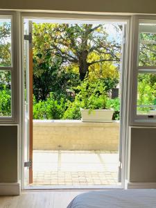 Une porte ouverte s'ouvre sur une terrasse avec un arbre. dans l'établissement One Oak Guest House, à Somerset West