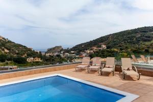 a swimming pool on a patio with chairs and a view at Palaiokastro Villas & Suites in Palaiokastro