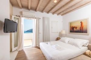 een witte slaapkamer met een groot bed en een tv bij Margi Villas in Mykonos-stad +116 foto's