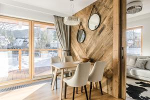 a dining room with a wooden wall and a table and chairs at RentPlanet - Luksusowe apartamenty Goszczyńskiego in Zakopane