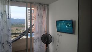 um quarto com uma janela, uma ventoinha e uma televisão em Apartamento en Reserva del Peñon Girardot. em Girardot