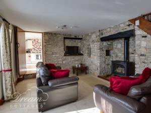 a living room with leather furniture and a stone wall at Blueberry Cottage in Weymouth
