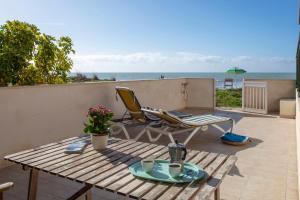 un patio con mesa, sillas y el océano en Terrazza Montalbano, en Punta Secca