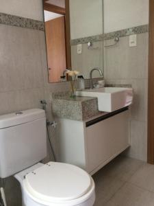 a bathroom with a white toilet and a sink at Apto incrível em condomínio lindo in Praia do Forte