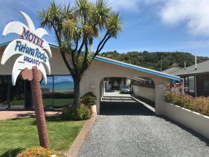 a motel entrance with a palm tree and a building at Futuna Rocks Motel in Kaikoura