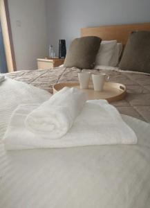 two towels on a bed with two cups on a tray at Diva Alojamento in Matosinhos