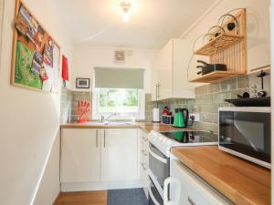 a small kitchen with white cabinets and a window at Sundowner in Caernarfon