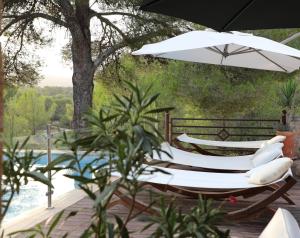 two chairs under an umbrella next to a pool at Finca Ses Eres in Artá