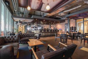 a bar with leather couches and tables in a restaurant at Fletcher Hotel-Restaurant Oss in Oss